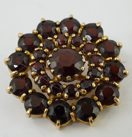 A 1970's 9ct gold and garnet cluster set circular brooch, 27mm. Condition - fair